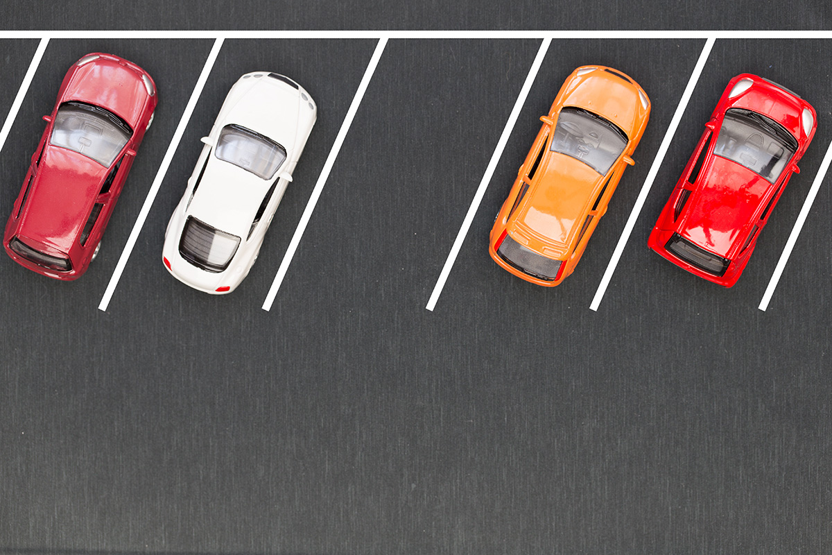 Cars parked in parking lot with neat stripes to demonstrate proper parking lot size.